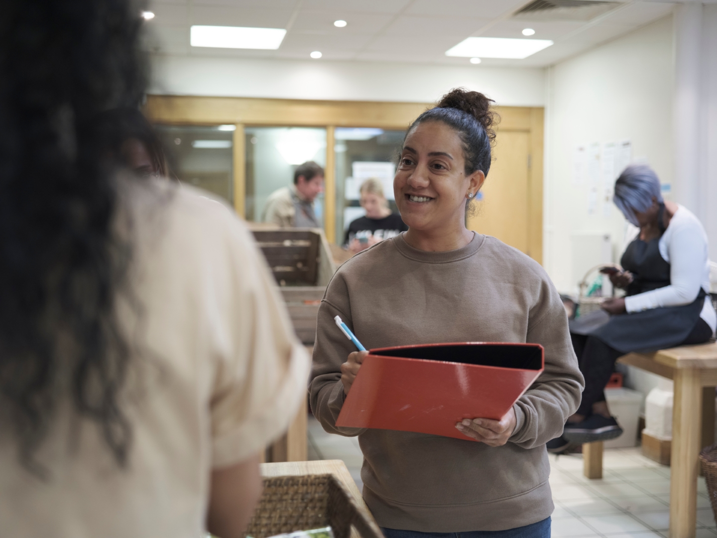 Volunteer worker smiling while holding a clipboard and pen