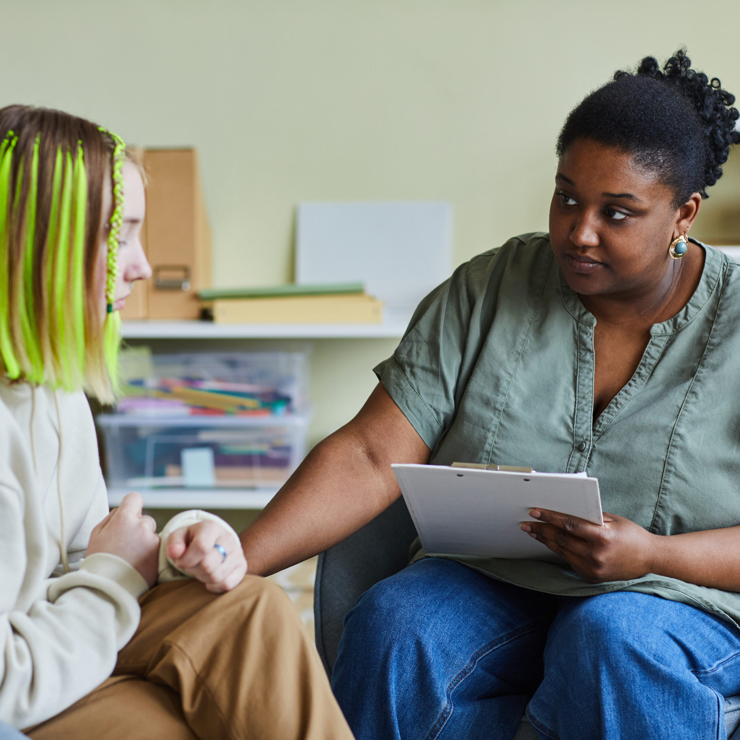 African female school psychologist supporting sad teenage girl during her difficult situation at school