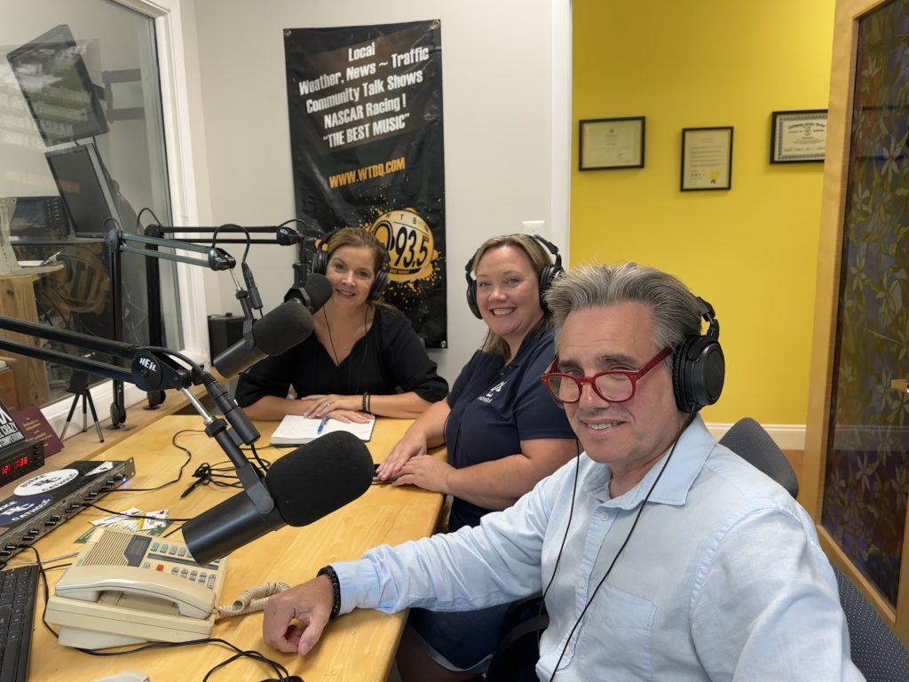 Three people in a recording radio studio in front of microphones