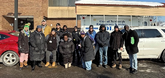 Group of volunteers and police officers standing outside City of Newburgh Police building during winter outreach event
